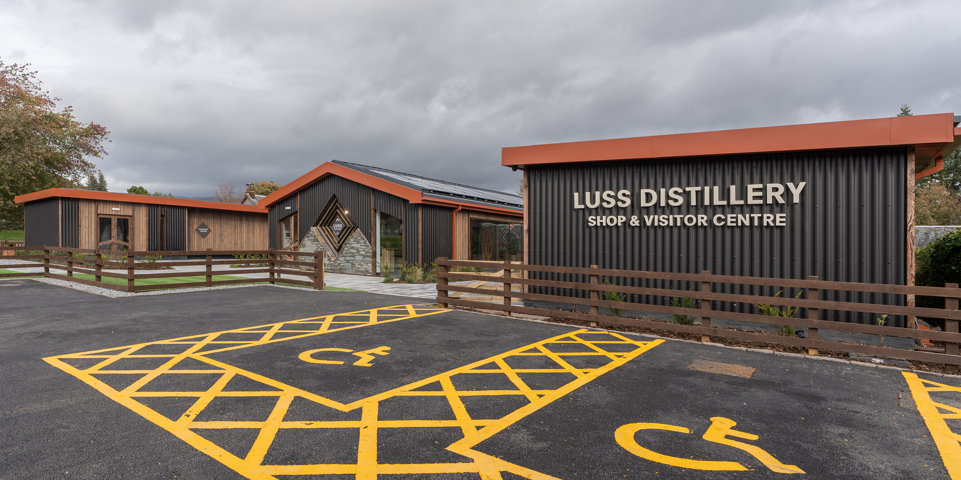 Parking area with wheelchair accessible symbol in front of a building with a geometric design.