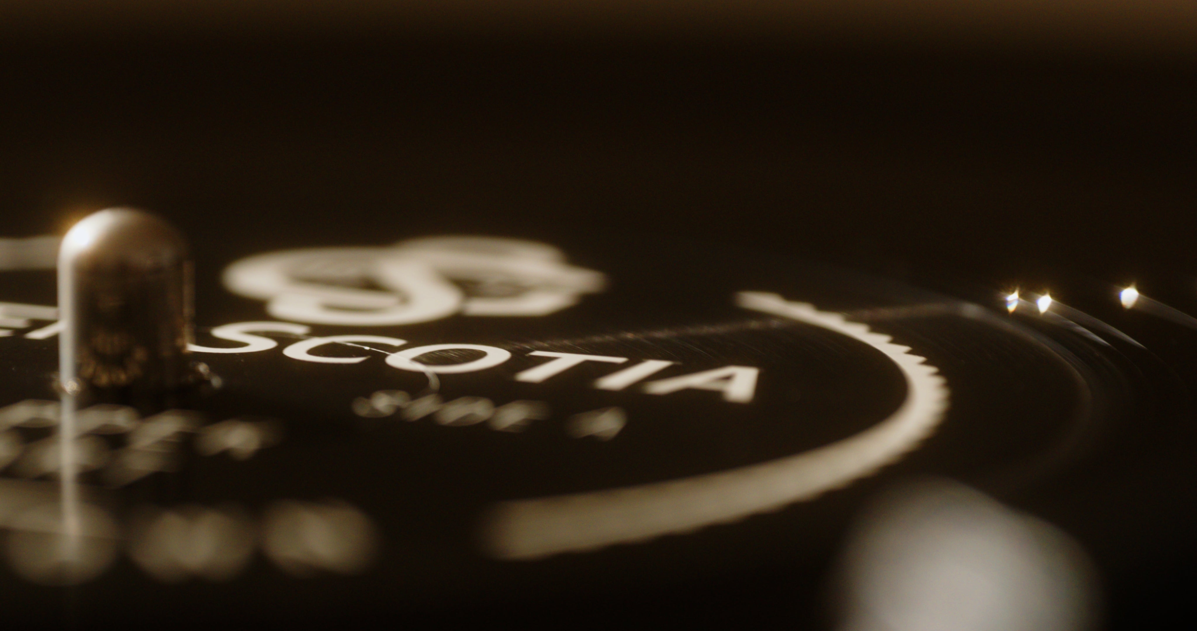 Close-up of a vinyl record. The photo focuses on a section near the center, showcasing part of the label with slightly blurred text and graphics. The words "The Sound of Glen Scotia" stand out, reminiscent of the rich heritage found in Campbeltown's Glen Scotia distillery. The grooves of the vinyl are slightly visible.