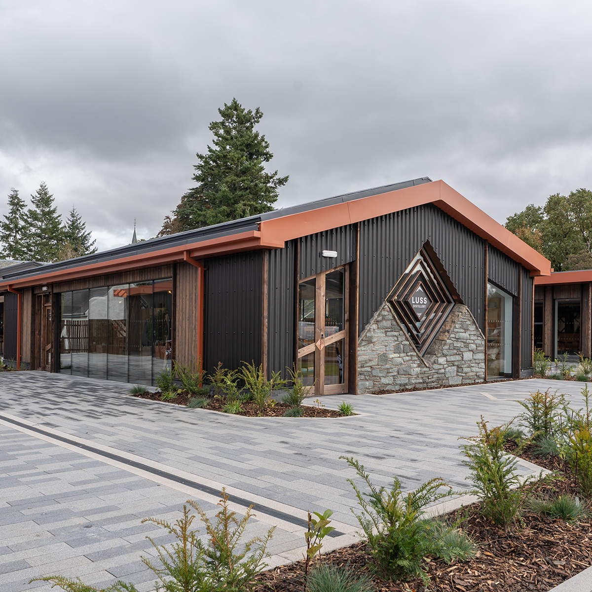 Modern building with a geometric design on the facade, surrounded by trees and a paved area.