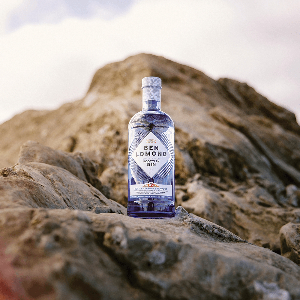 Ben Lomond Scottish Gin bottle on a rocky surface with a mountainous background