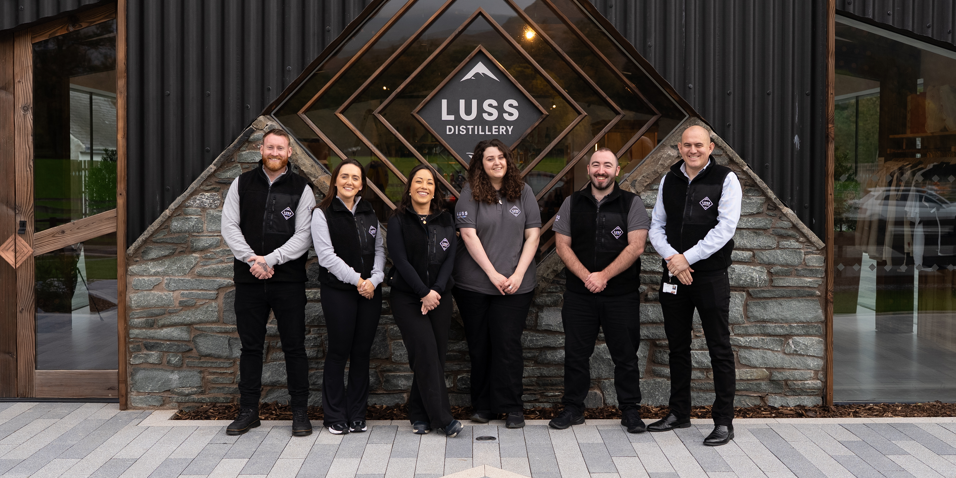 Group of people standing in front of the LUSS Distillery entrance.